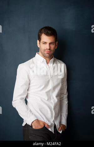 Portrait von entspannter junge Unternehmer an Kamera suchen Bei dunklem Hintergrund stehen. Stockfoto