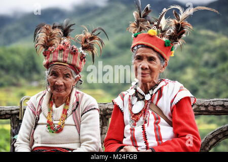 Banaue, Philippines-October 8, 2016: Einige ältere Ifugaos - Männer und Frauen - noch Kleid in ihrer traditionellen Kleidung und Kopfbedeckung während der Sitzung durch die r Stockfoto