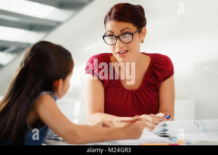 Bildung mit Mama hilft Tochter tun Schule Hausaufgaben zu Hause Stockfoto