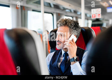 Reifen Geschäftsmann mit Smartphone, der mit dem Zug reist. Stockfoto