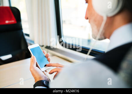 Reifen Geschäftsmann mit Smartphone, der mit dem Zug reist. Stockfoto