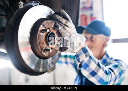 Senior Mechanikerin Instandsetzung ein Auto in eine Garage. Stockfoto