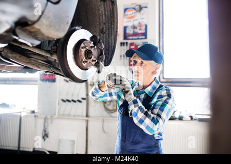 Senior Mechanikerin Instandsetzung ein Auto in eine Garage. Stockfoto