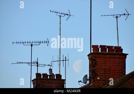 Antennen und Schornsteine auf London Häuser mit einem großen Mond hinter Stockfoto