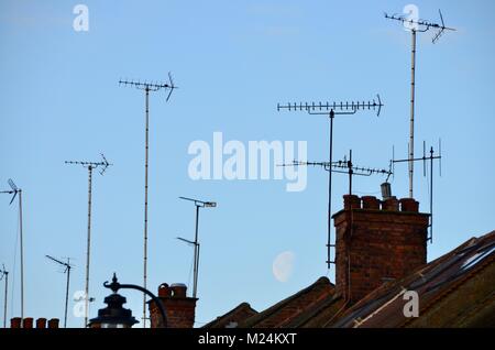 Antennen und Schornsteine auf London Häuser mit einem großen Mond hinter Stockfoto