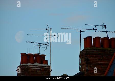 Antennen und Schornsteine auf London Häuser mit einem großen Mond hinter Stockfoto