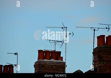 Antennen und Schornsteine auf London Häuser mit einem großen Mond hinter Stockfoto