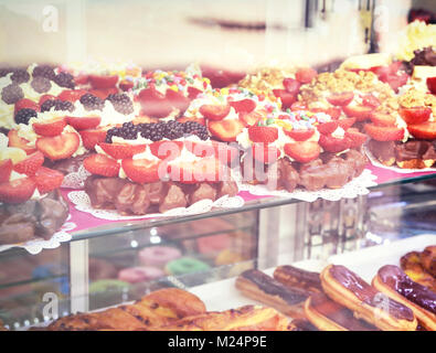 Süße Speisen hinter einer Bäckerei Fenster. Eclairs, Backwaren und Obst Kuchen, Dessert oder Süßigkeiten. Stockfoto