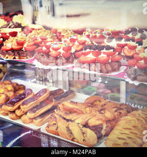 Süße Speisen hinter einer Bäckerei Fenster. Eclairs, Backwaren und Obst Kuchen, Dessert oder Süßigkeiten. Stockfoto