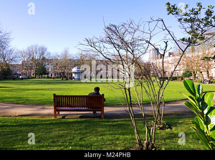 Ein Student auf einer Bank sitzen auf seiner Mittagspause genießen Sie den Sonnenschein in Abercromby Square Liverpool UK. Stockfoto