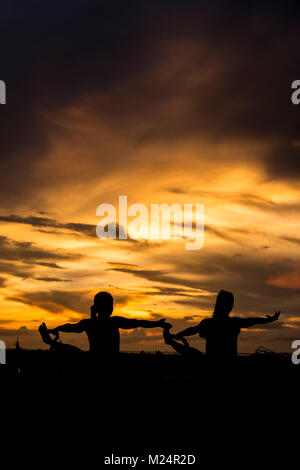 Yoga am Strand während einer spektakulären Sonnenuntergang Stockfoto