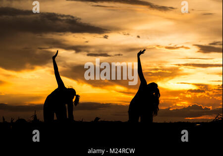 Yoga am Strand während einer spektakulären Sonnenuntergang Stockfoto