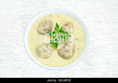Griechische frikadelle Suppe, bekannt als youvarlakia, auf weissem Holztisch Stockfoto