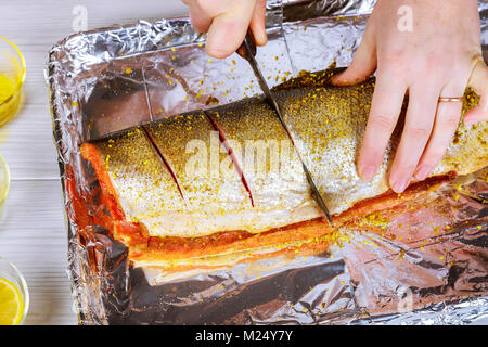 Frauen Hände bereiten Lachs Schiefergestein auf metallischen Hintergrund. Blick von oben. Vorbereitung für das Kochen Fisch essen. Frau Koch. Stockfoto