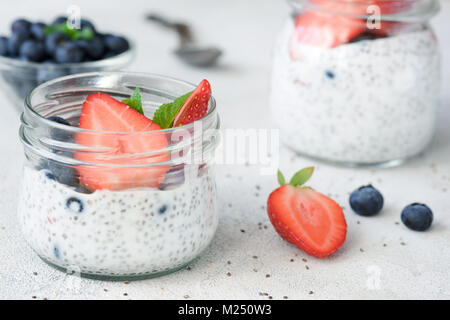 Chia Samen Milchreis mit frischen Blaubeeren und Erdbeeren auf weißer Tisch. Detailansicht. Das Nähren, Detox, gesunden Lebensstil und Gewicht-verlust-Konzept Stockfoto