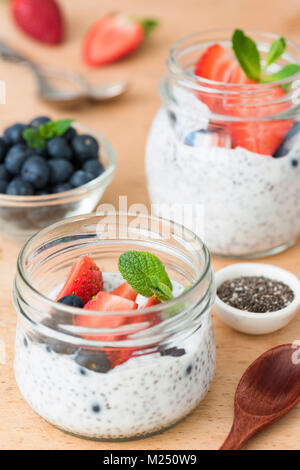 Chia Samen Milchreis mit frischen Erdbeeren und Blaubeeren auf hölzernen Tisch. Selektive konzentrieren. Konzept des Nährens, sauber essen, gesunde Lebensweise und wir Stockfoto