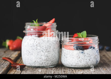 Chia Samen Milchreis mit frischen Erdbeeren und Blaubeeren auf rustikalen Holztisch mit Platz für Text kopieren Stockfoto