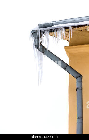 Ecke des Hauses mit Fallrohr. eiszapfen Herunterhängen vom Dach. Stockfoto