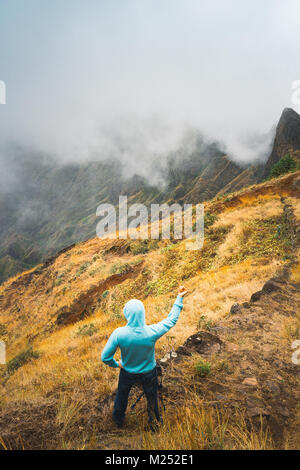 Reisende, der auf den gepflasterten Pfad und bewundern Sie Wolken über die Berge ins Tal fließt. Santo Antao Insel in Cabo Verde Stockfoto