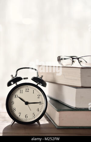 Wecker, Bücher und Brillen auf Tisch Stockfoto