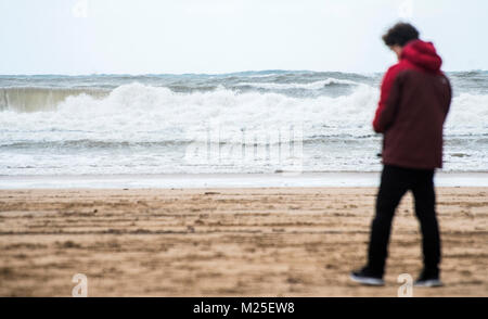 Gijon, Spanien. 05. Januar, 2018. Ein Mann geht auf den Strand San Lorenzo in Gijon, während eines Tages, der starken Brunnen auf dem Meer. Im Norden von Spanien ist in Alarm durch den Schnee, Regen, Flügel und Schwellen. © David Gato/Alamy leben Nachrichten Stockfoto