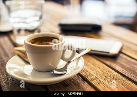 Kaffee. Tasse Kaffee Handy am Tisch im Restaurant Café Terrasse. Kaffeepause. Stockfoto