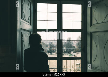 Frau auf der Suche durch das Fenster, getönten Bild, Vintage Style. Stadtbild von Turin, Turin, Italien, altes Haus, Ansicht von hinten in den Schatten. Stockfoto