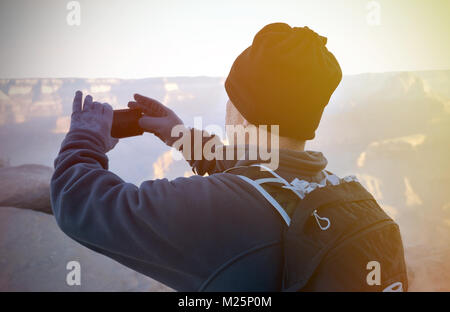 Wanderer mit Smartphone unter Morgen panormic Bilder unterwegs im Grand Canyon mit Sun Flair auf der Seite Stockfoto