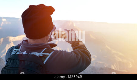 Wanderer mit Smartphone unter Morgen panormic Bilder unterwegs im Grand Canyon mit Sun Flair auf der Seite Stockfoto