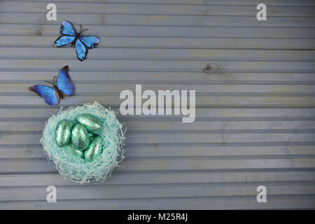 Ostern Dekorationen mit Nest von Schokolade Eier und Frühling Schmetterlinge Stockfoto