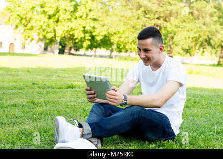 Lächelnden jungen Mann mit Tablette im Park Stockfoto