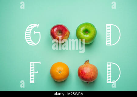 Hand Schrift Essen auf Türkisfarbenem Hintergrund mit Obst Orange Grün rote Äpfel Granatapfel. Gesunde, saubere Essen vegane Vitamine Energiekonzept. Stockfoto