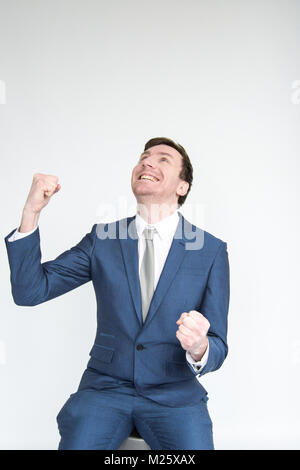 Ein sehr aufgeregt, gut gekleideter Mann im Anzug stanzen die Luft in Triumph an eine Ausführung. portrait isoliert auf weißem Hintergrund Stockfoto