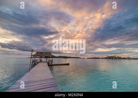 Tropischen Strand, Karibik, glasklares türkisfarbenes Wasser, remote Togean Inseln (togian Inseln), Sulawesi, Indonesien. Dramatische Himmel bei Sonnenuntergang. Stockfoto