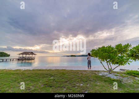 Touristische am tropischen Strand bei Sonnenuntergang, remote Togean Inseln (togian Inseln), Sulawesi, Indonesien, upgrowing Reiseziel. Stockfoto