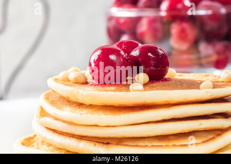 Pfannkuchen hausgemachte Kuchen mit Beeren gefroren Cherry dekoriert Stack und Pinienkernen auf weiße Platte Stockfoto