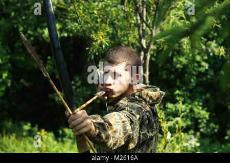 Junge Bogenschütze Jäger mit Pfeil und Bogen schießen im Sommer Wald Stockfoto