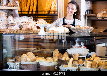 Gerne weibliches Personal verkaufen frisches Gebäck und Baguettes in der örtlichen Bäckerei Stockfoto