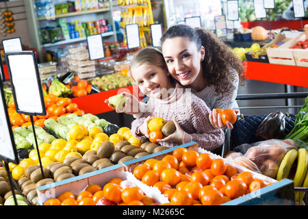 Junge Frau mit Tochter Einkauf Früchte und lächelnd auf den Markt Stockfoto