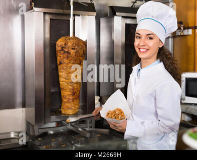Professionelle heiter lächelnd weibliche Kochen mit gegrilltem Fleisch am Spieß für Kebab Stockfoto