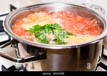 Hinzufügen von gehackten gruenen Gemüsesuppe Stockfoto