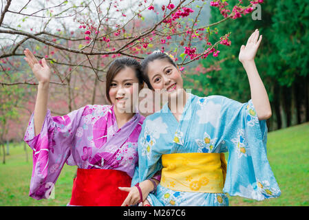 Schönen lächelnden Frauen Freunde tragen traditionellen Kimono, Reise nach Japan und besuchen Sakura blühenden Park, Geste, c Stockfoto