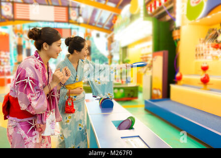 Attraktive junge Frau spielen Frisbee Spiel, wenn Sie tragen Kimonos Reisen in Japan zusammen während der Sommerferien. Stockfoto