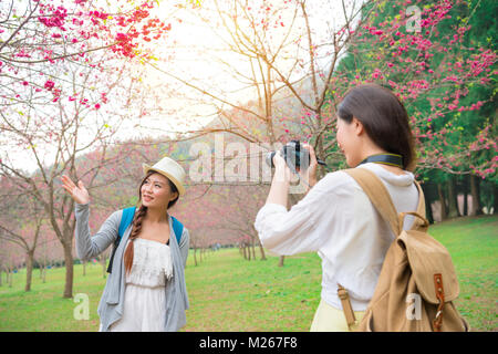 Junge schöne Frau mit Kamera helfen, Freundin, wenn Sie in Japan Reisen und Besuchen cherry Blooming Flower Park. Stockfoto