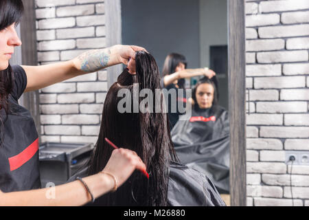 Weibliche Friseur macht einen Abschied und Kämme nasse Haare brünette Frau, während sie im Sessel sitzt im Schönheitssalon Stockfoto