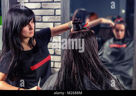 Professionelle Friseur schneiden und Modellierung braunes Haar der Junge brünette Frau, während sie sitzt in einem Sessel im Beauty Salon Stockfoto