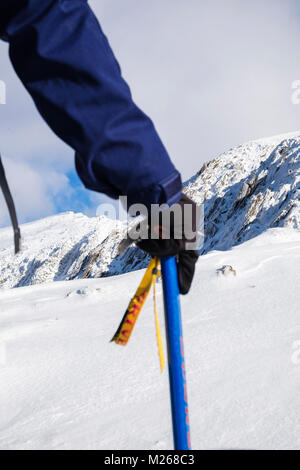 Wanderer mit einem Eispickel in der Hand wandern auf Rhyd Ddu Route mit Blick auf Mt Snowdon im Winter Schnee in Snowdonia National Park Gwynedd Wales UK Großbritannien Stockfoto