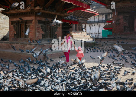 Mutter und Kleinkind Mädchen zu Fuß am Durbar Square, Kathmandu, Nepal von fliegenden Straße Tauben umgeben Stockfoto