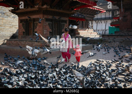 Mutter und Kleinkind Mädchen zu Fuß am Durbar Square, Kathmandu, Nepal von fliegenden Straße Tauben umgeben Stockfoto