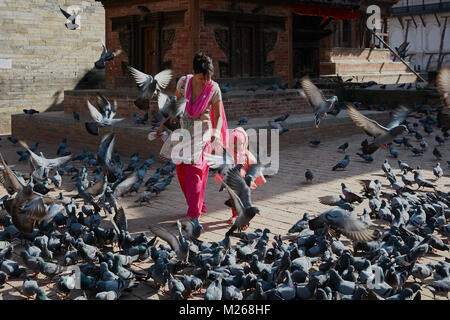 Mutter und Kleinkind Mädchen zu Fuß am Durbar Square, Kathmandu, Nepal von fliegenden Straße Tauben umgeben Stockfoto